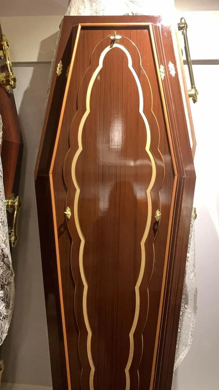 Urna funerária em mogno com entalhe ondulado e acabamento clássico.