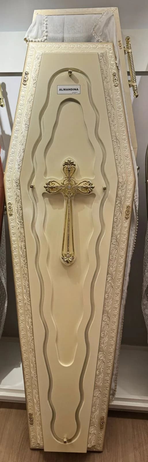 Destaque de urna funerária clara com crucifixo dourado