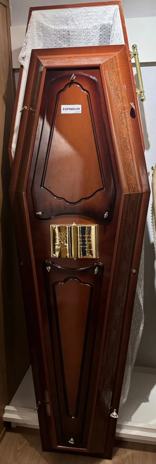 Urna funerária Espinélio em acabamento escuro com placa frontal decorativa.